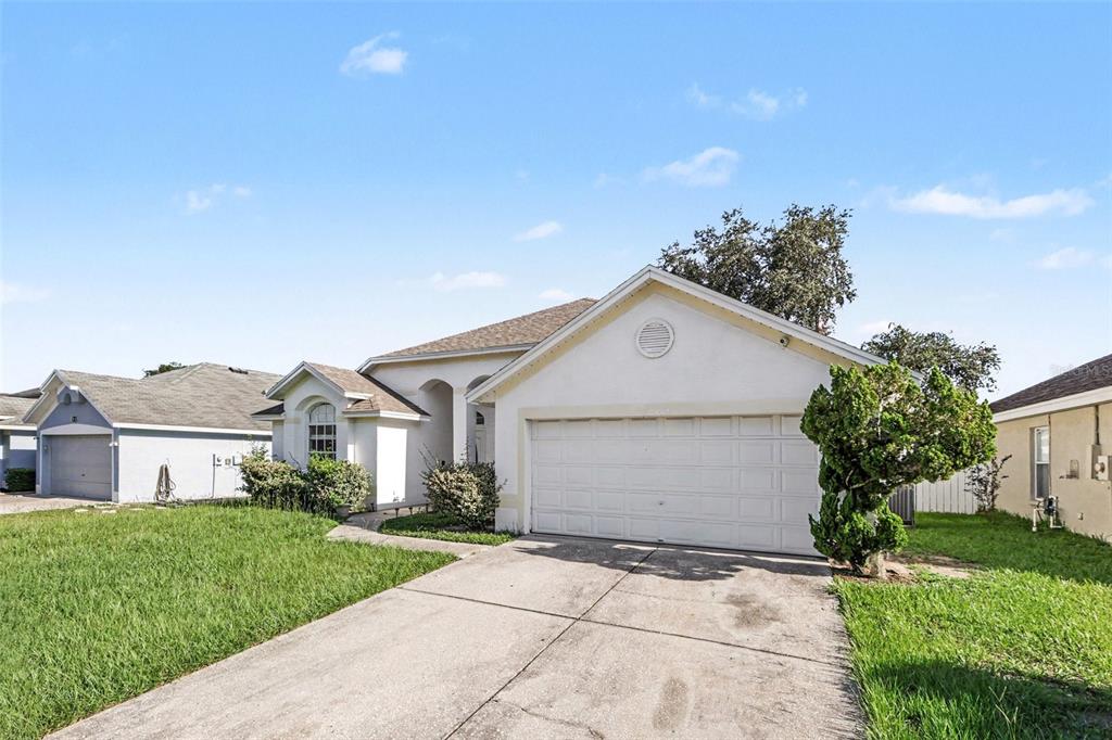 A single-story house with a white stucco exterior, a two-car garage, and a concrete driveway — 28809 WINDOVER ST, WESLEY CHAPEL, FL