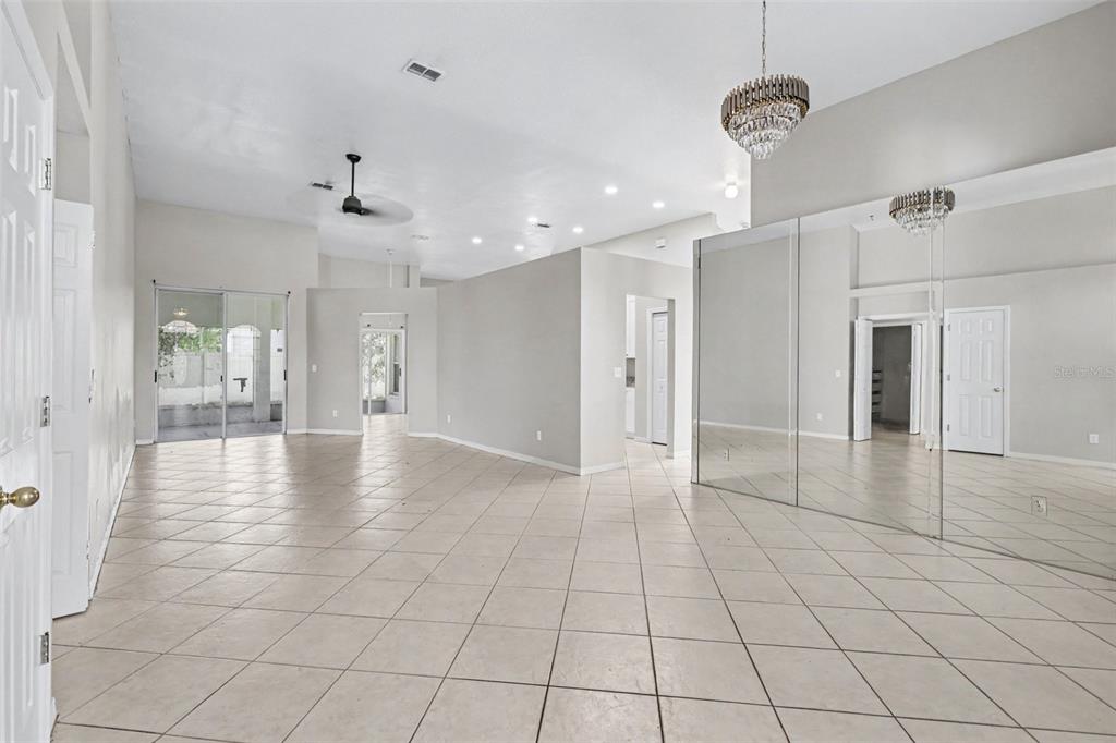 A spacious, tiled living area features high ceilings, a mirrored wall, and a crystal chandelier — 28809 WINDOVER ST, WESLEY CHAPEL, FL