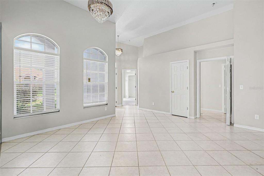 A bright, tiled room features high ceilings, two arched windows, and two crystal chandeliers — 28809 WINDOVER ST, WESLEY CHAPEL, FL