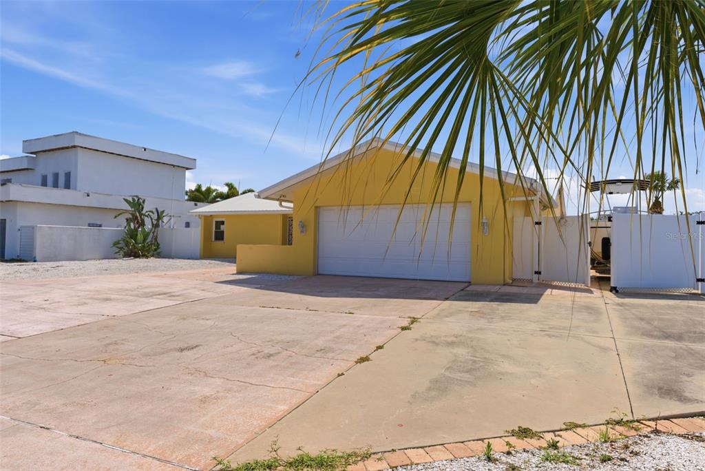 A yellow house with a two-car garage and a large concrete driveway — 1421 SEA GULL DRIVE S, ST PETERSBURG, FL