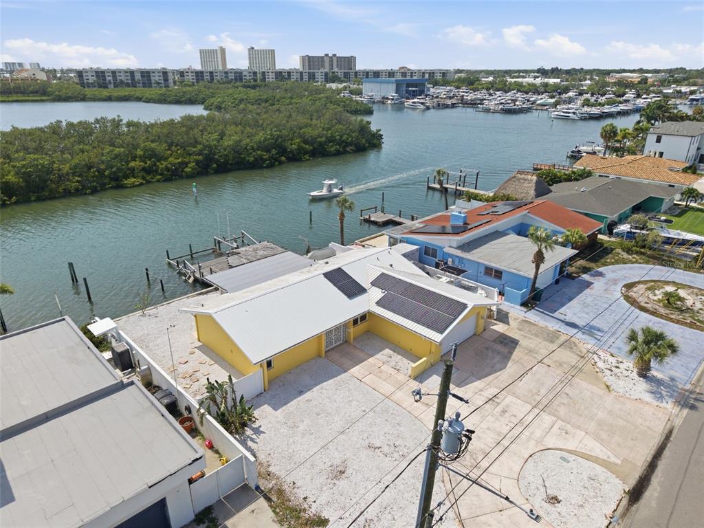 An aerial view shows a yellow waterfront house with solar panels and a private dock — 1421 SEA GULL DRIVE S, ST PETERSBURG, FL