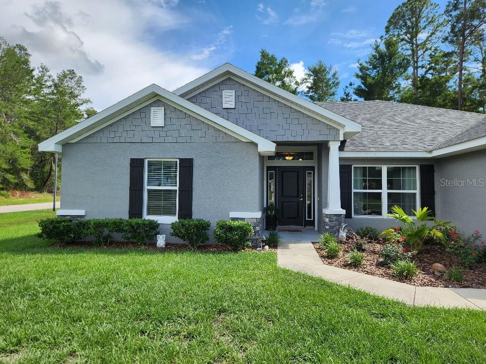 A gray single-story house features a shingled gable, black shutters, and a covered front entryway — 47 VILLAGE CENTER DRIVE, HOMOSASSA, FL