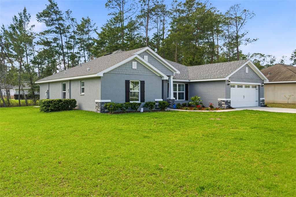 A gray single-story house with a two-car garage and a large front lawn — 47 VILLAGE CENTER DRIVE, HOMOSASSA, FL