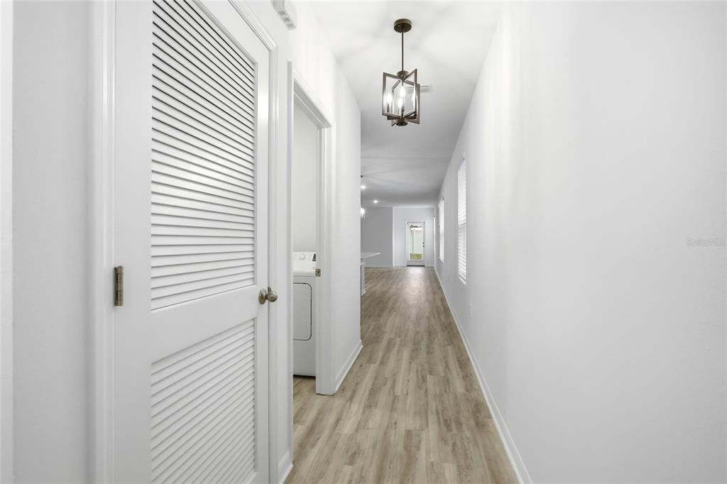 A hallway with light wood-look flooring, white walls, a louvered door, and a pendant light — 5735 MOUNTAIN ROAD, DAVENPORT, FL