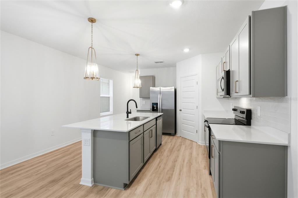 A kitchen features gray cabinets, white countertops, a central island, and light wood-look flooring — 5735 MOUNTAIN ROAD, DAVENPORT, FL