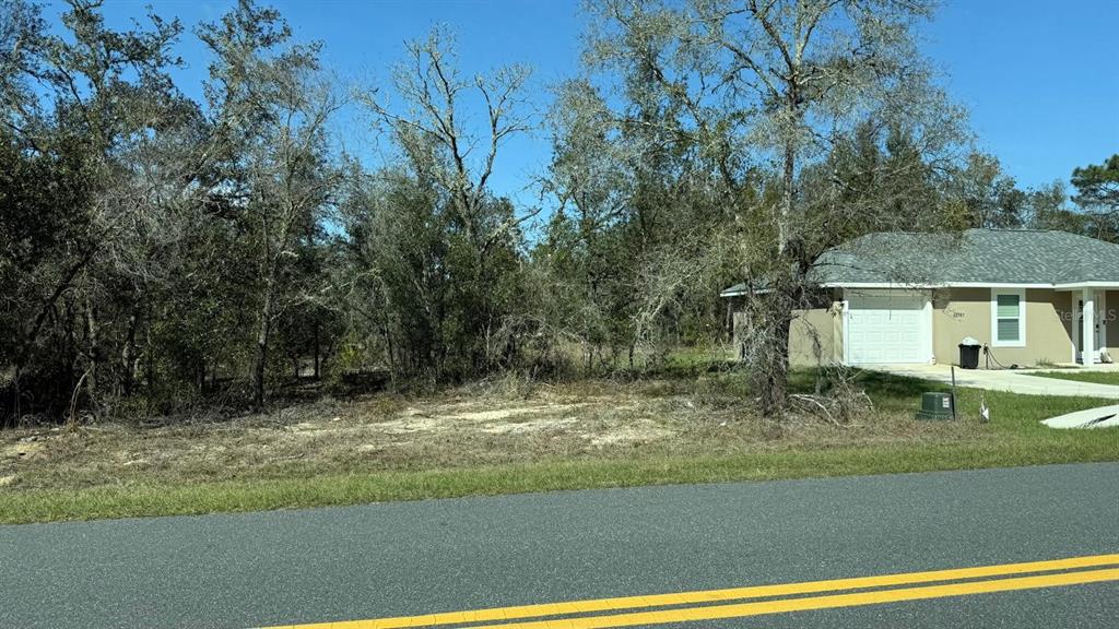 A vacant, wooded residential lot sits next to a single-story house with a garage — 22767 SW BEACH BOULEVARD, DUNNELLON, FL