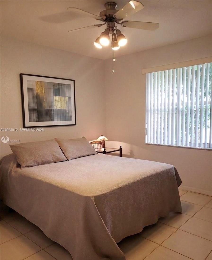 A bedroom features a bed with a tan cover, a ceiling fan, and vertical blinds — 15989 SW 149th Ter # 15989, Miami FL 33196, MIAMI, FL