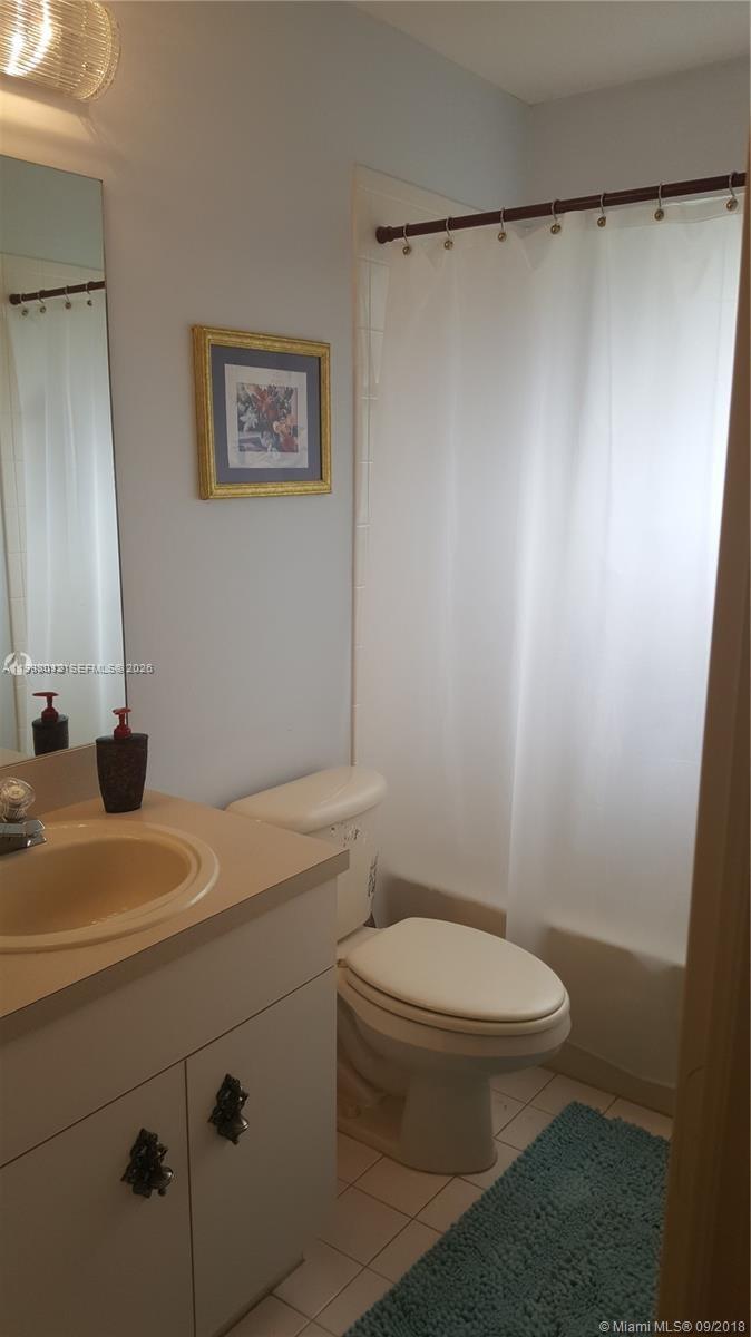 A bathroom features a vanity with a beige countertop, a toilet, and a shower curtain — 15989 SW 149th Ter # 15989, Miami FL 33196, MIAMI, FL