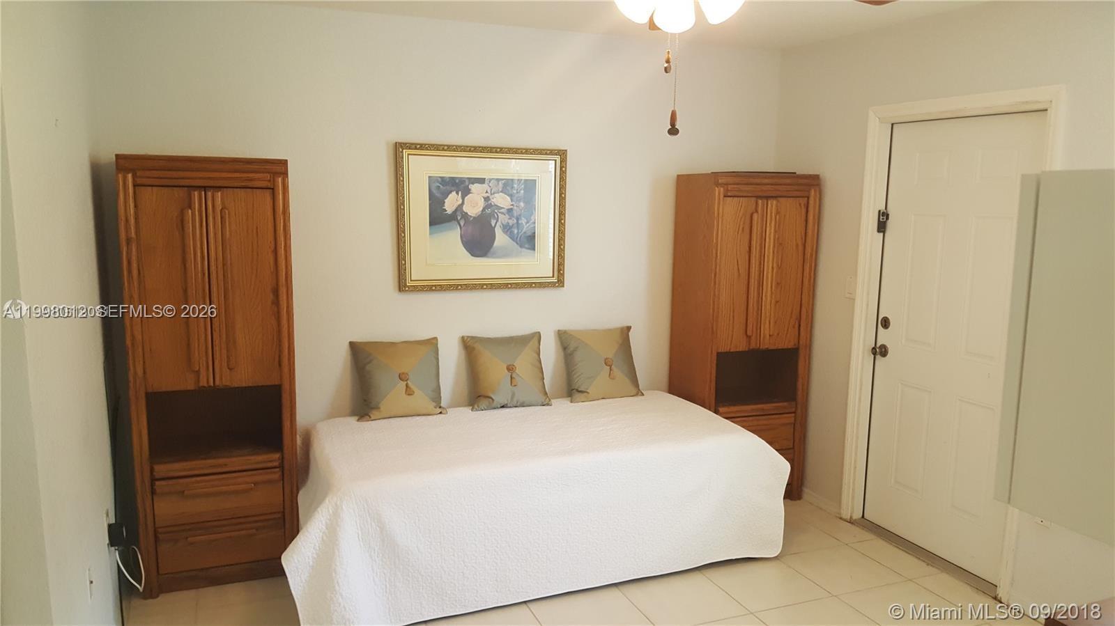 A bedroom features a daybed between two wooden cabinets, a framed picture, and tiled flooring — 15989 SW 149th Ter # 15989, Miami FL 33196, MIAMI, FL