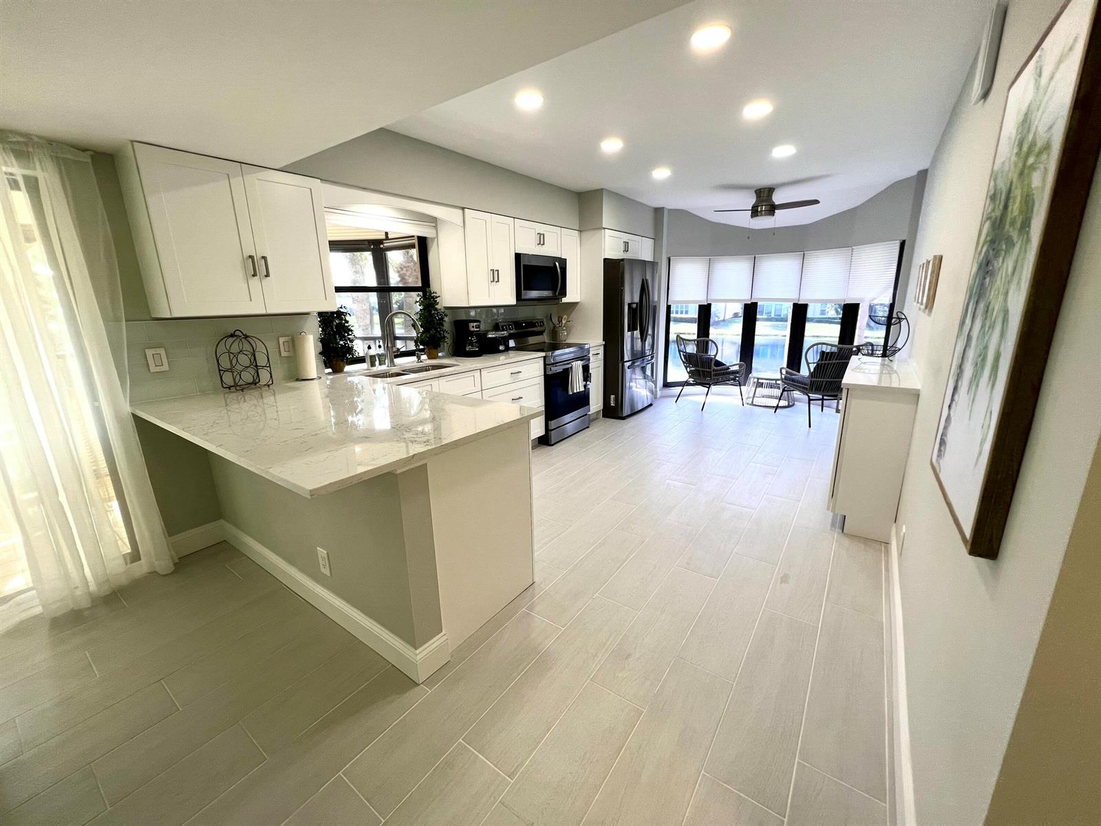 A modern kitchen features white cabinets, marble countertops, stainless steel appliances, and light tile flooring — 17081 Waterbend Dr Drive Unit 229, Jupiter FL 33477, JUPITER, FL