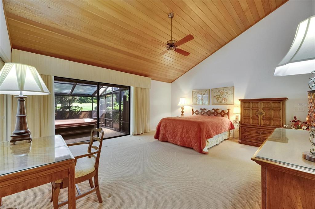 A bedroom with a vaulted wood ceiling, carpeted floors, and a sliding door to a patio — 29903 BAYWOOD LANE, WESLEY CHAPEL, FL