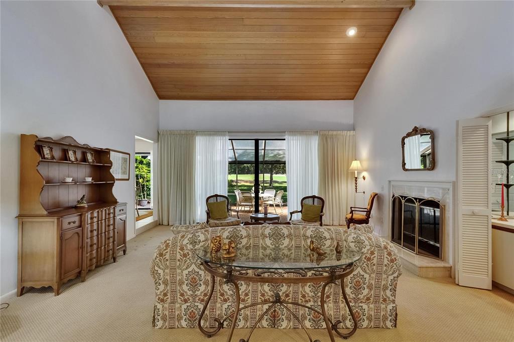 A living room features a vaulted wood-paneled ceiling, a fireplace, and a glass-topped console table — 29903 BAYWOOD LANE, WESLEY CHAPEL, FL