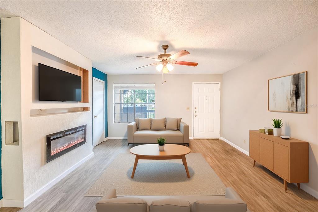 A living room features a fireplace, a wall-mounted television, light wood flooring, and a ceiling fan — 360 LAKE ONTARIO COURT UNIT 202, ALTAMONTE SPRINGS, FL