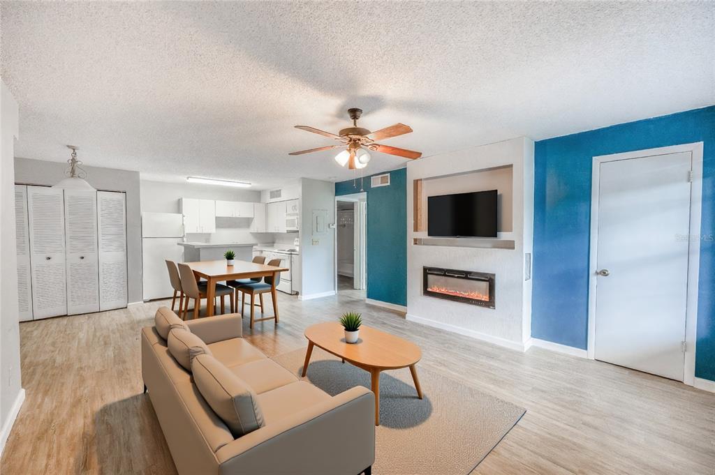 An open-concept living and dining area features light wood flooring, a fireplace, and blue walls — 360 LAKE ONTARIO COURT UNIT 202, ALTAMONTE SPRINGS, FL