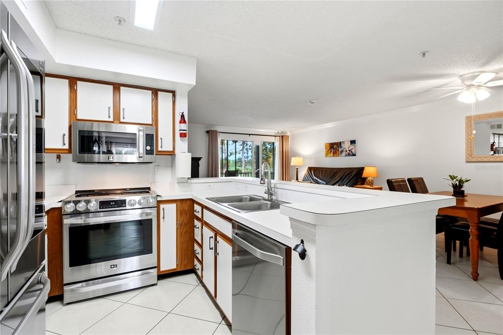 A kitchen with white cabinets, stainless steel appliances, and a breakfast bar with wooden stools — 2400 FEATHER SOUND DRIVE UNIT 427, CLEARWATER, FL