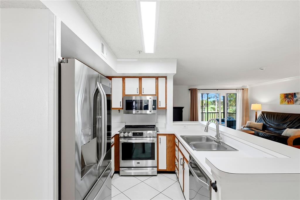 A living and dining area with tile floors, a wooden table, and a sliding glass door — 2400 FEATHER SOUND DRIVE UNIT 427, CLEARWATER, FL