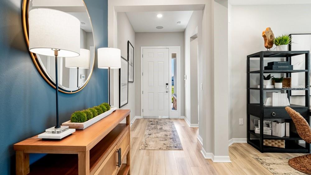 An entryway features a wood console table, blue accent wall, round mirror, and black shelving — 12817 DOCKYARD TRAIL, PALMETTO, FL