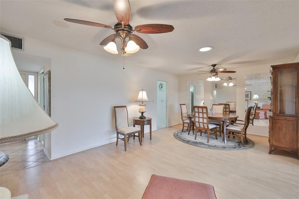 A dining area with a round table, chairs, ceiling fans, and light wood flooring — 1525 ALLEGHENY DRIVE, SUN CITY CENTER, FL