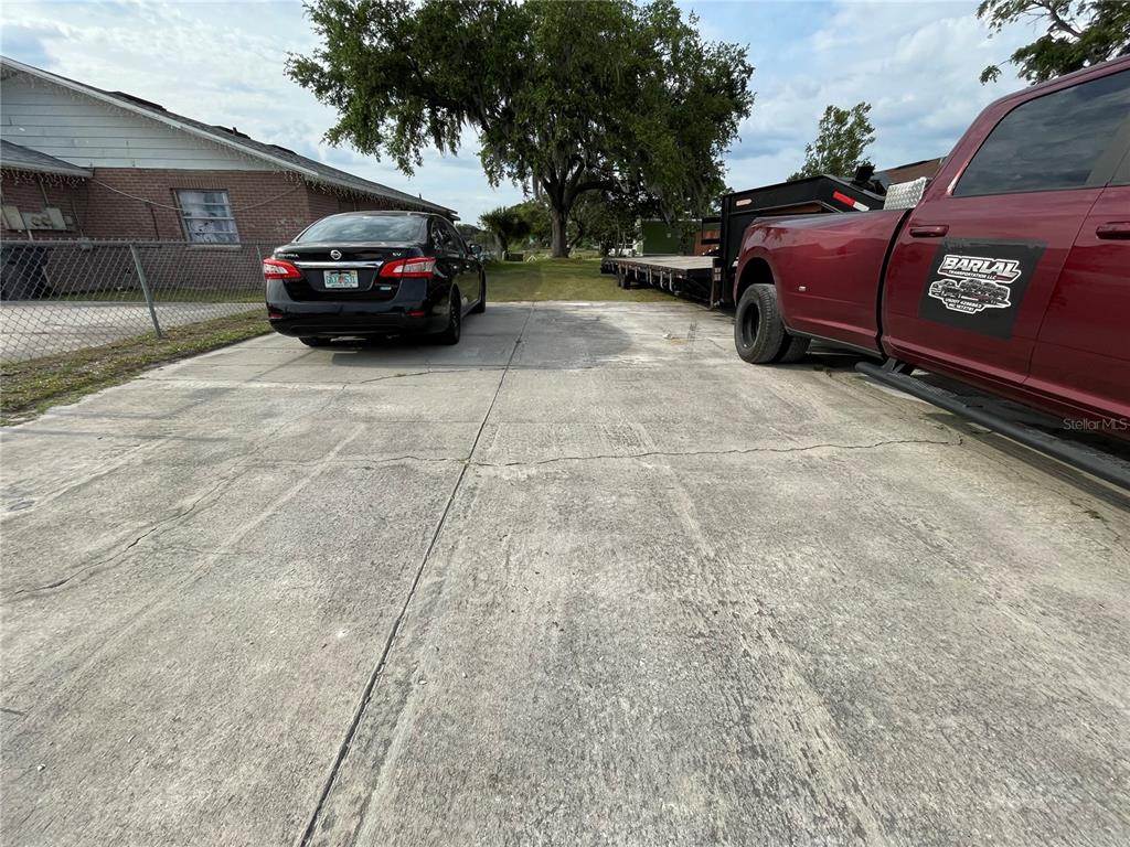A concrete driveway features a parked black sedan and a red truck with a trailer — SKYVIEW DRIVE, LAKELAND, FL