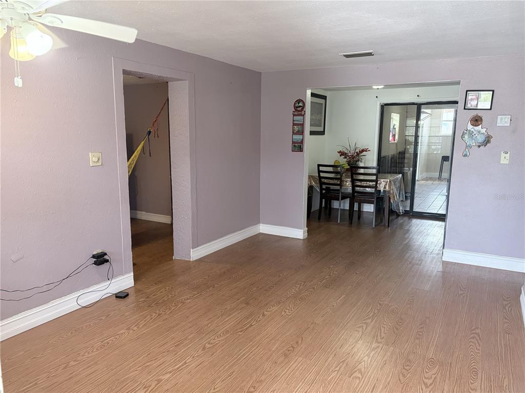 A living room with light wood-look flooring, lavender walls, and an adjacent dining area — 4802 E CURTIS STREET, TAMPA, FL