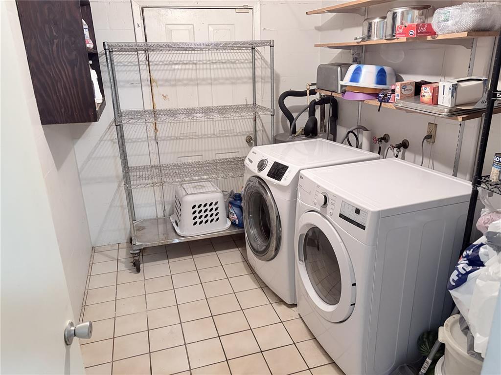 A laundry room features a white washer and dryer, metal shelving, and tiled flooring — 4802 E CURTIS STREET, TAMPA, FL