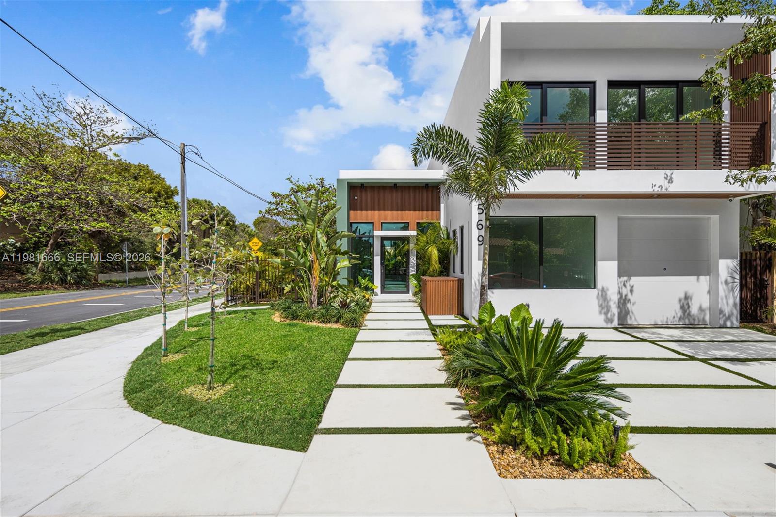 A modern two-story house features a white exterior, wood accents, and a paved driveway — 569 NW 44th St, Miami FL 33127, MIAMI, FL