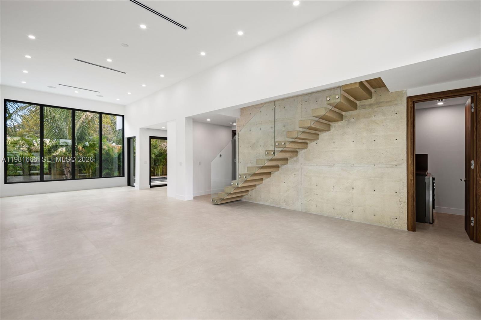 A modern, minimalist room features a floating wooden staircase against a raw concrete wall — 569 NW 44th St, Miami FL 33127, MIAMI, FL