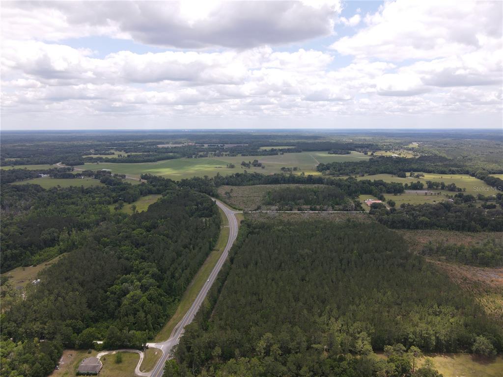 An aerial view shows a rural road winding through dense forests and open agricultural fields — TBD N STATE ROAD 121, ALACHUA, FL