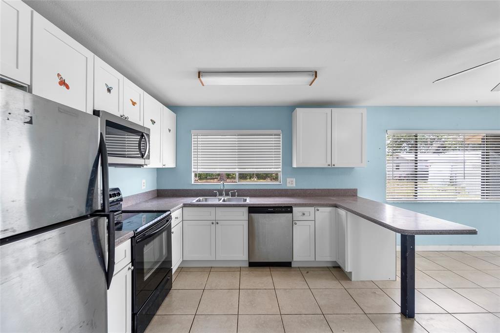 A kitchen with white cabinets, stainless steel appliances, light blue walls, and tile flooring — 4577 MARALDO AVENUE, NORTH PORT, FL