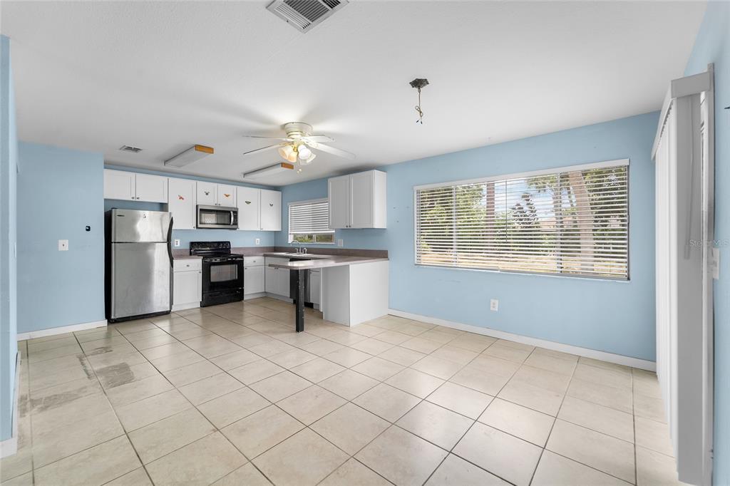A kitchen with white cabinets, stainless steel appliances, and light blue walls over tiled floors — 4577 MARALDO AVENUE, NORTH PORT, FL