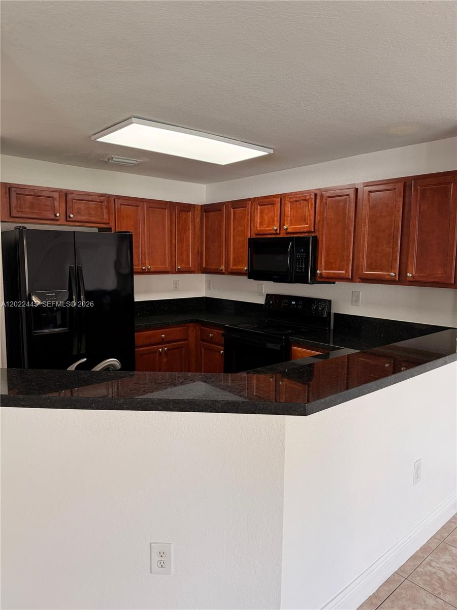 A kitchen features dark wood cabinets, black appliances, and a black granite countertop — 3172 SW 128th Ter # 148, Miramar FL 33027, MIRAMAR, FL