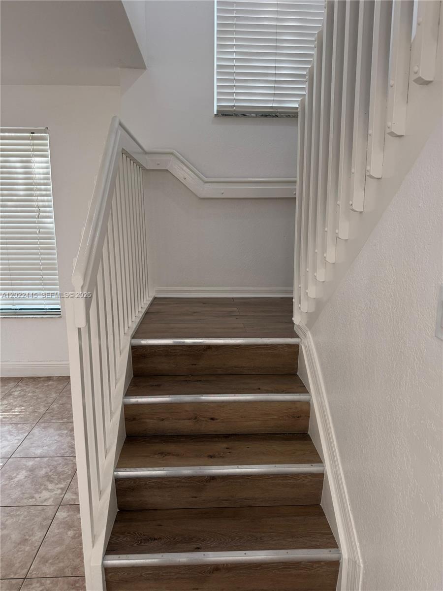 A staircase with wood-look treads and white railings leads to a landing with blinds — 3172 SW 128th Ter # 148, Miramar FL 33027, MIRAMAR, FL