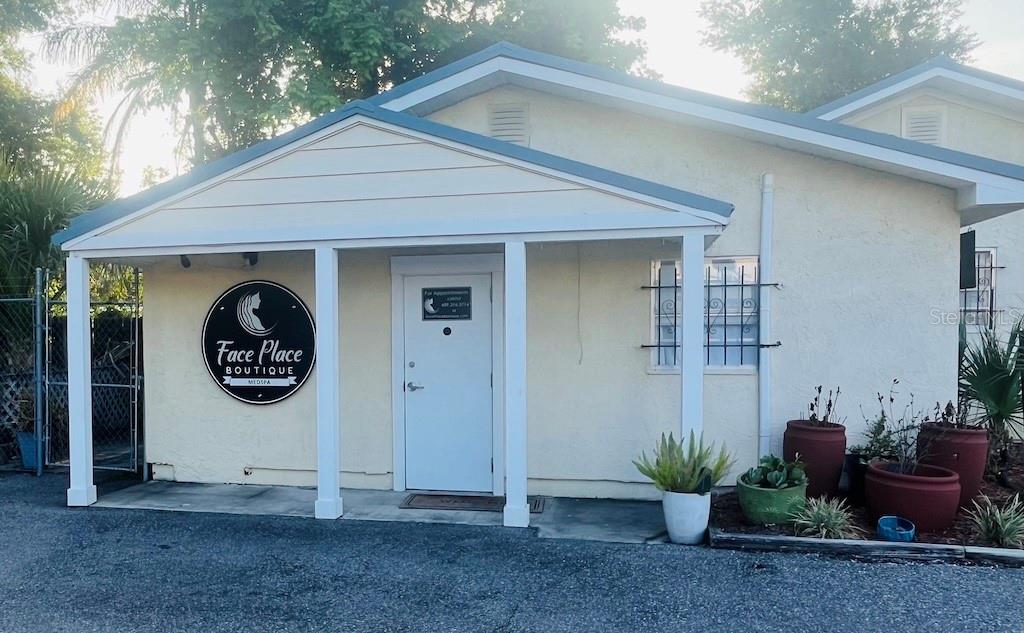 The exterior of a light-colored building features a covered entrance with a circular business sign — 2515 E SOUTH STREET, ORLANDO, FL