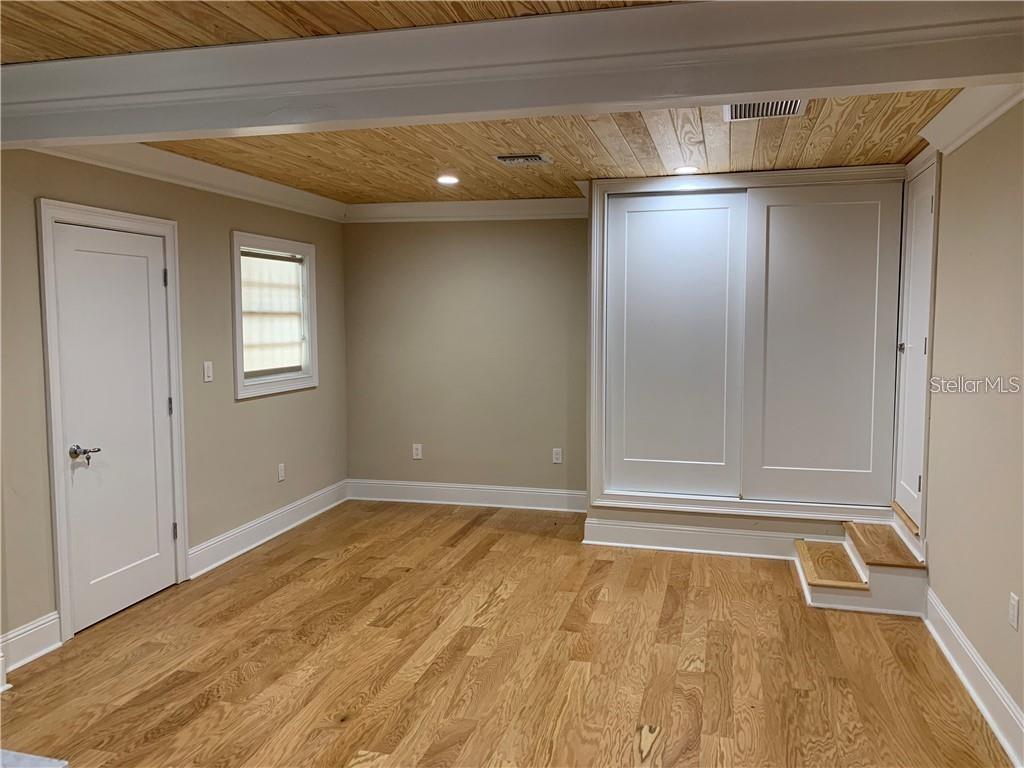 A room with light wood flooring, a wood-paneled ceiling, and a raised white closet area — 2515 E SOUTH STREET, ORLANDO, FL