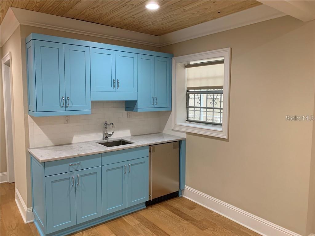 A kitchen features bright blue cabinets, a marble countertop, a stainless steel dishwasher, and wood-paneled ceiling — 2515 E SOUTH STREET, ORLANDO, FL