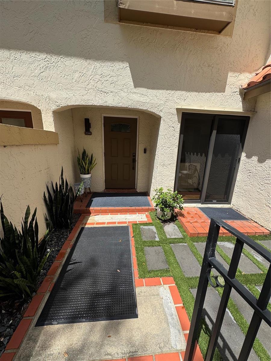 An exterior view shows a brown front door, sliding glass doors, and a tiled walkway — 7741 La Mirada Drive, Boca Raton FL 33433, BOCA RATON, FL