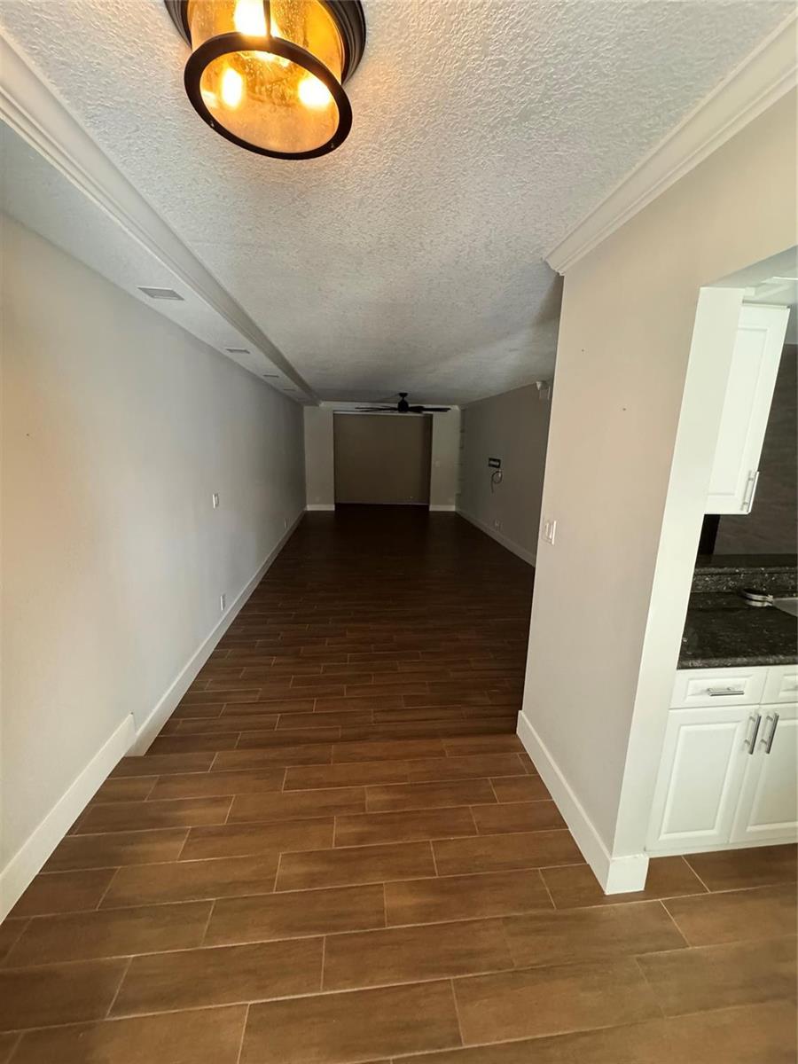 A long, narrow room features wood-look tile flooring and a ceiling-mounted light fixture — 7741 La Mirada Drive, Boca Raton FL 33433, BOCA RATON, FL