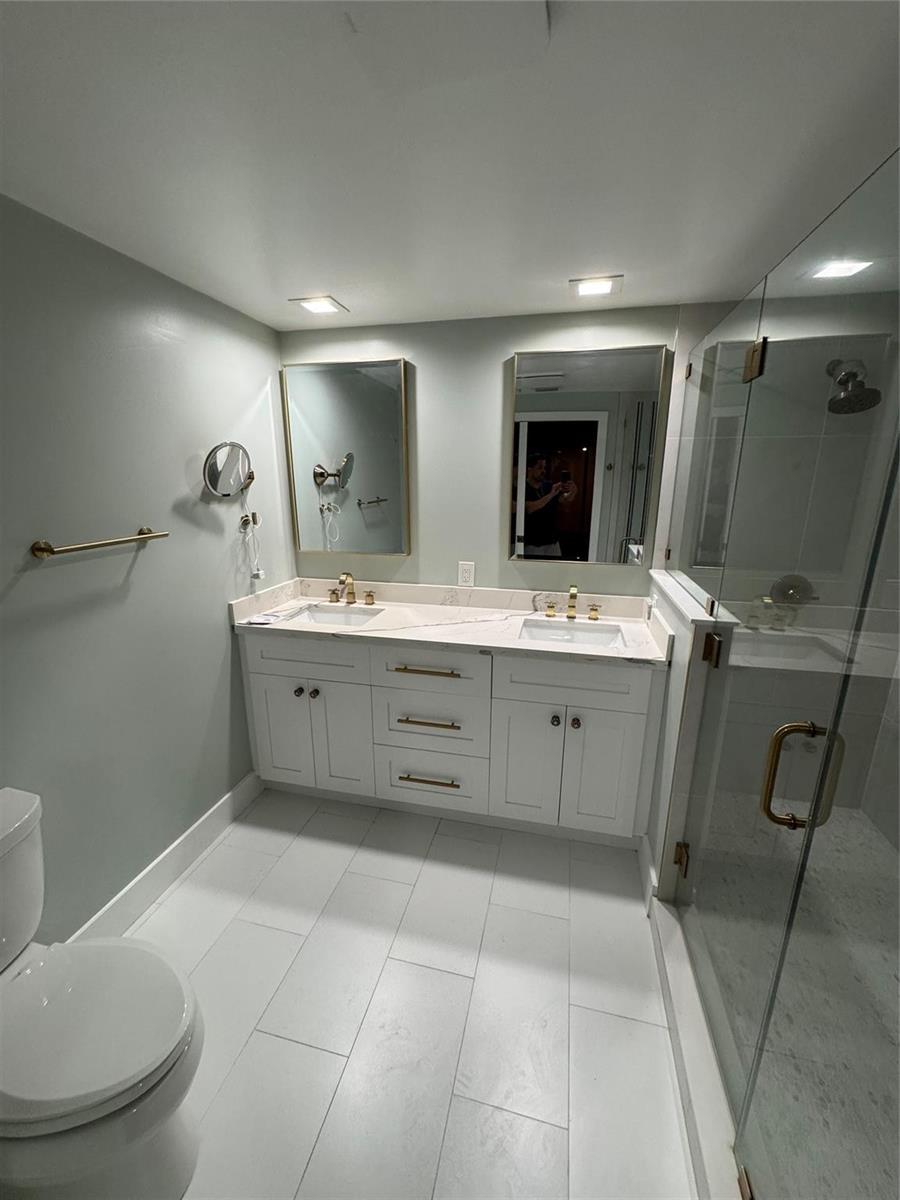 A bathroom features a double vanity with white cabinets, gold hardware, and two framed mirrors — 7741 La Mirada Drive, Boca Raton FL 33433, BOCA RATON, FL