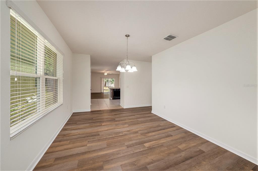 A dining area with wood-look flooring, a chandelier, and a view into the kitchen — 10212 HAWK STORM AVENUE, TAMPA, FL