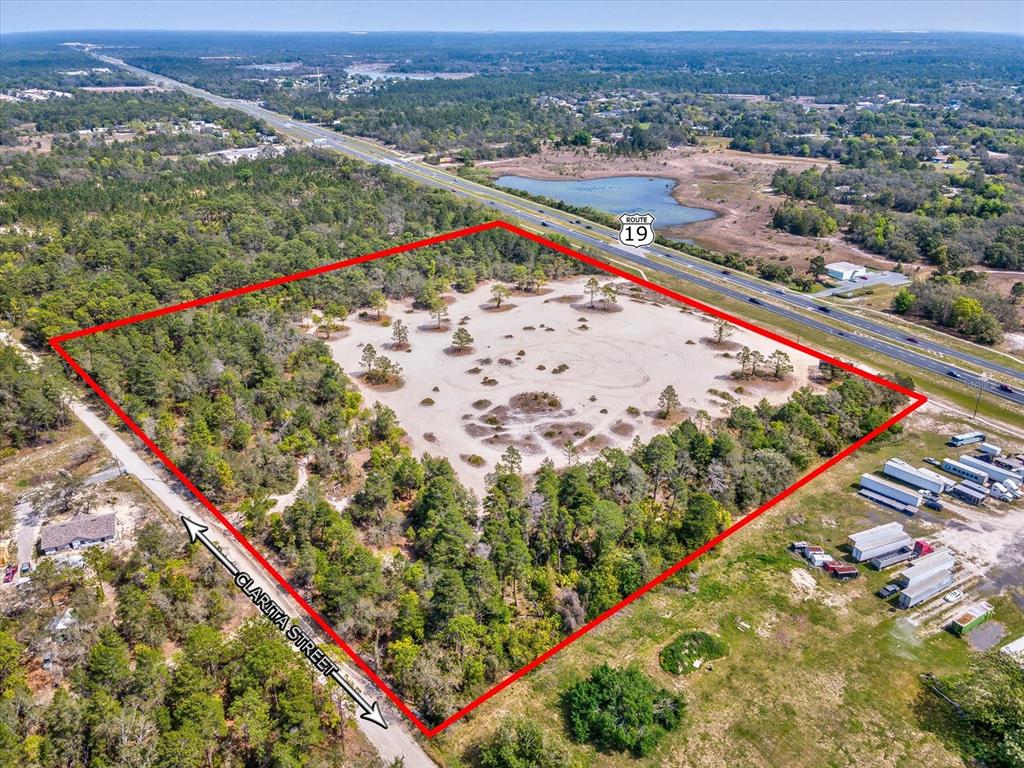 An aerial view shows a large, rectangular, sandy plot of land bordered by trees — 15.7 Acres COMMERCIAL WAY, WEEKI WACHEE, FL