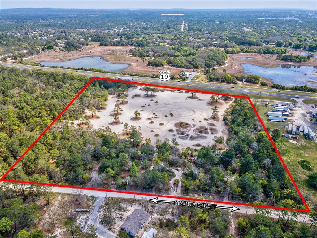 An aerial view shows a large, cleared sandy lot outlined in red near a highway — 15.7 Acres COMMERCIAL WAY, WEEKI WACHEE, FL