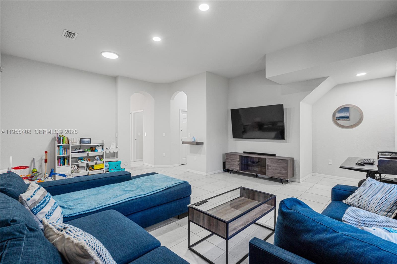 A living room features blue sectional sofas, a glass coffee table, and a wall-mounted television — 1940 SE 24th Ter, Homestead FL 33035, HOMESTEAD, FL