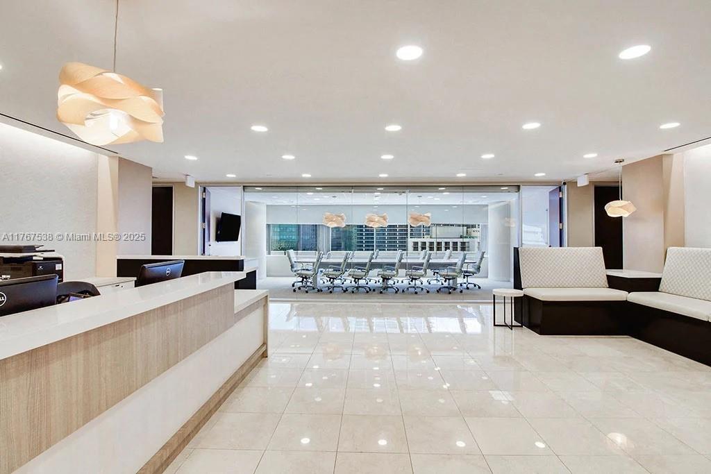 A modern office reception area features a white desk, tiled floors, and a glass-enclosed conference room — 100 SE 2 ST # 2000, Miami FL 33131, MIAMI, FL