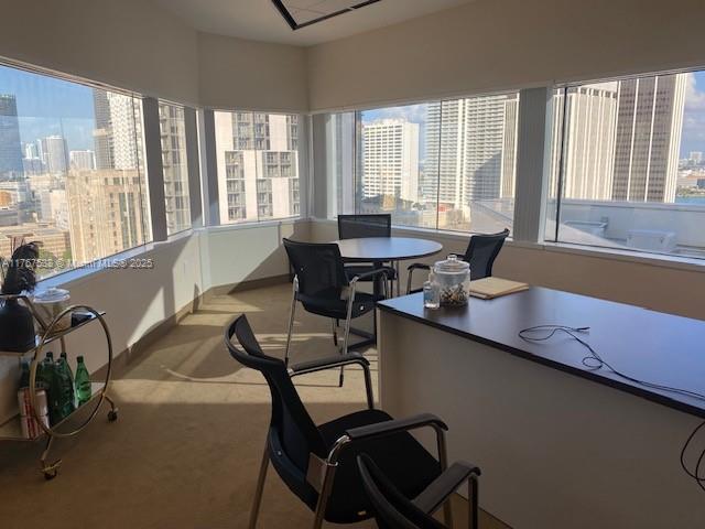 An office with a desk, chairs, and a bar cart overlooking a city skyline — 100 SE 2 ST # 2000, Miami FL 33131, MIAMI, FL