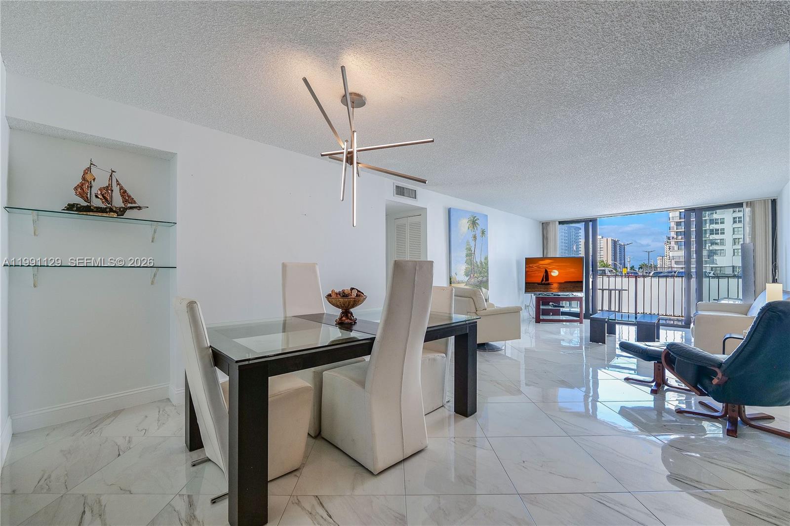 A dining area and living room feature white marble floors, modern furniture, and a balcony — 2401 S Ocean Dr # 305, Hollywood FL 33019, HOLLYWOOD, FL
