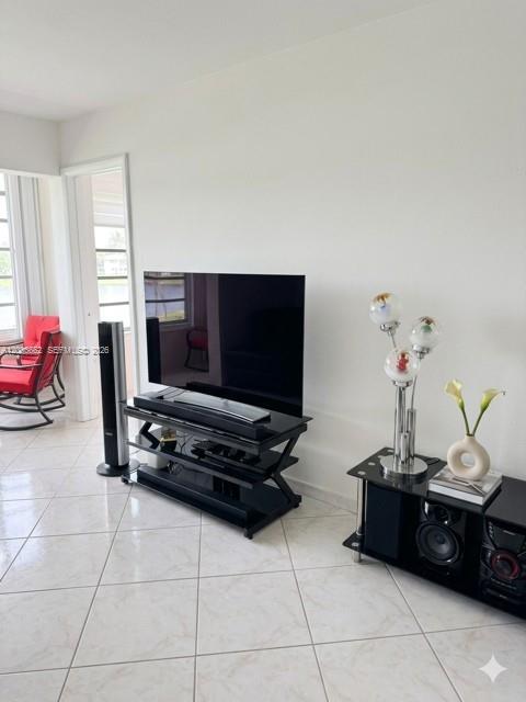 A living room features a television on a black stand, a speaker, and a rocking chair — 1530 NE 191st St # 305, Miami FL 33179, MIAMI, FL