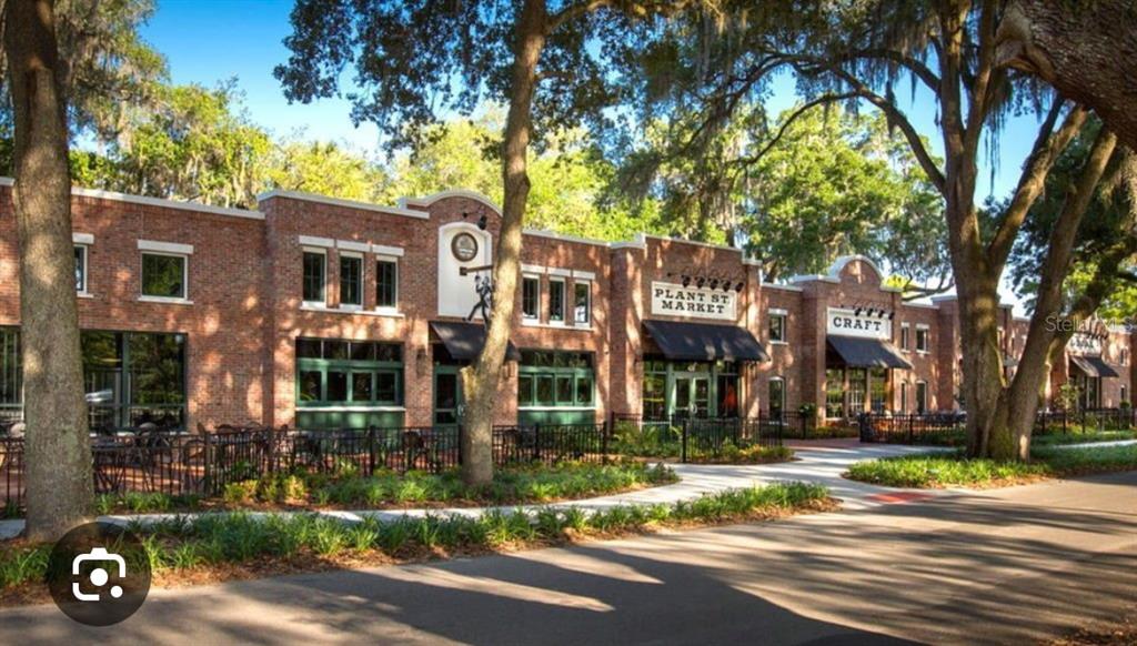 A brick commercial building with black awnings and outdoor seating under large oak trees — 47 OAK STREET, WINTER GARDEN, FL