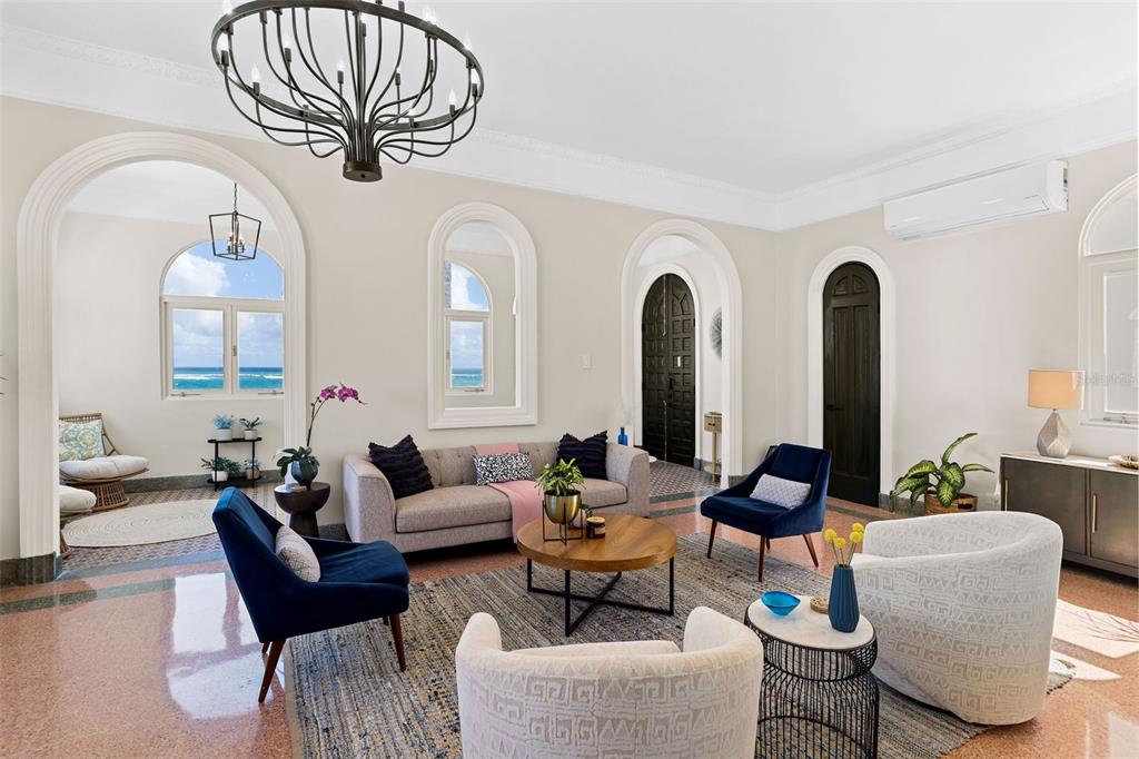 A living room features arched doorways, a chandelier, blue armchairs, and a view of the ocean — 1506 ASHFORD UNIT PH, SAN JUAN, PR