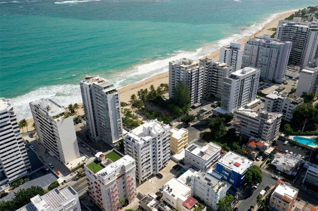 An aerial view of high-rise apartment buildings situated along a sandy beach and ocean — 1506 ASHFORD UNIT PH, SAN JUAN, PR
