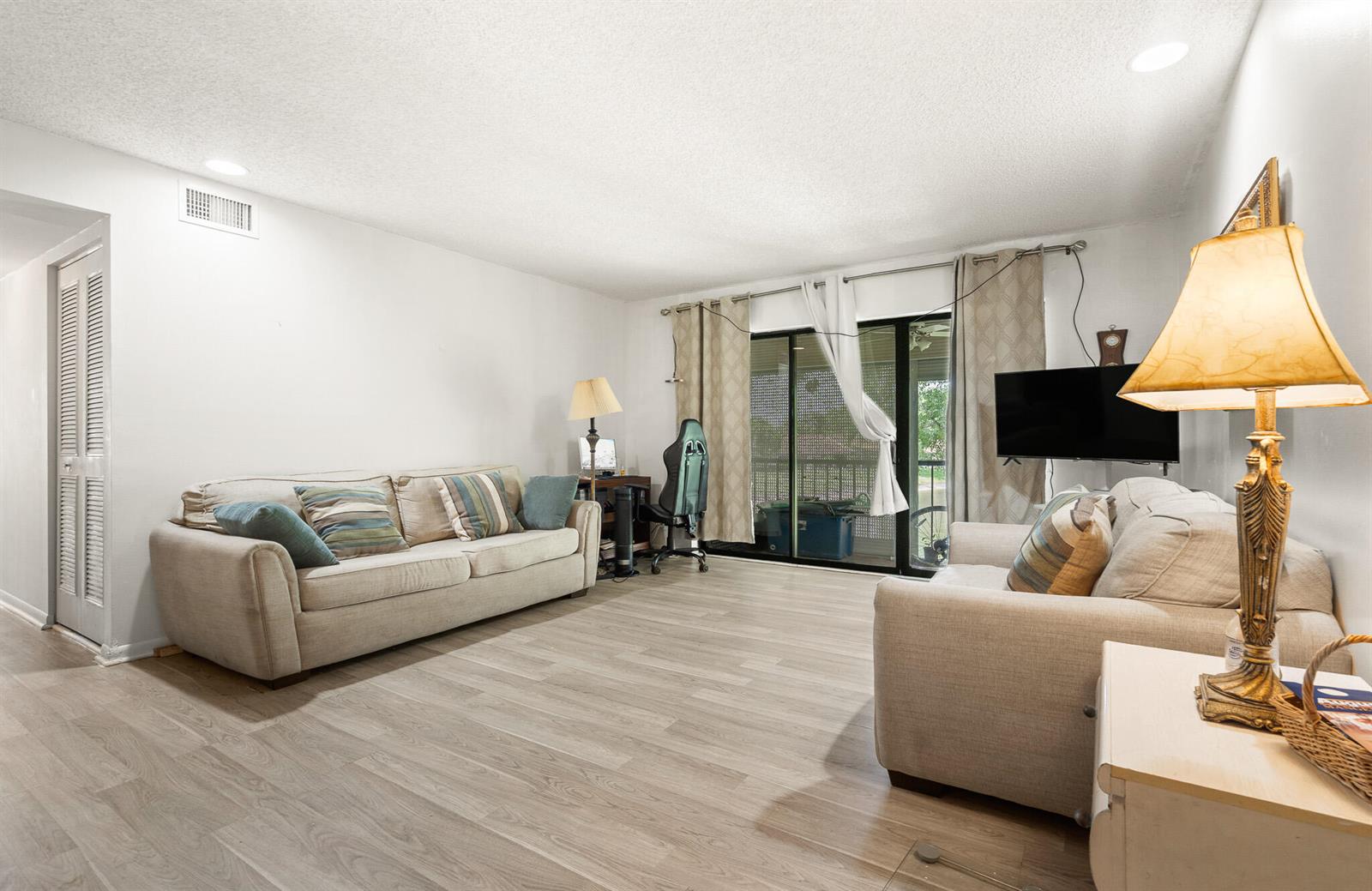 A living room features light wood-look flooring, two beige sofas, and a sliding glass door — 610 Sea Pine Way # H2, FL 33415, FL